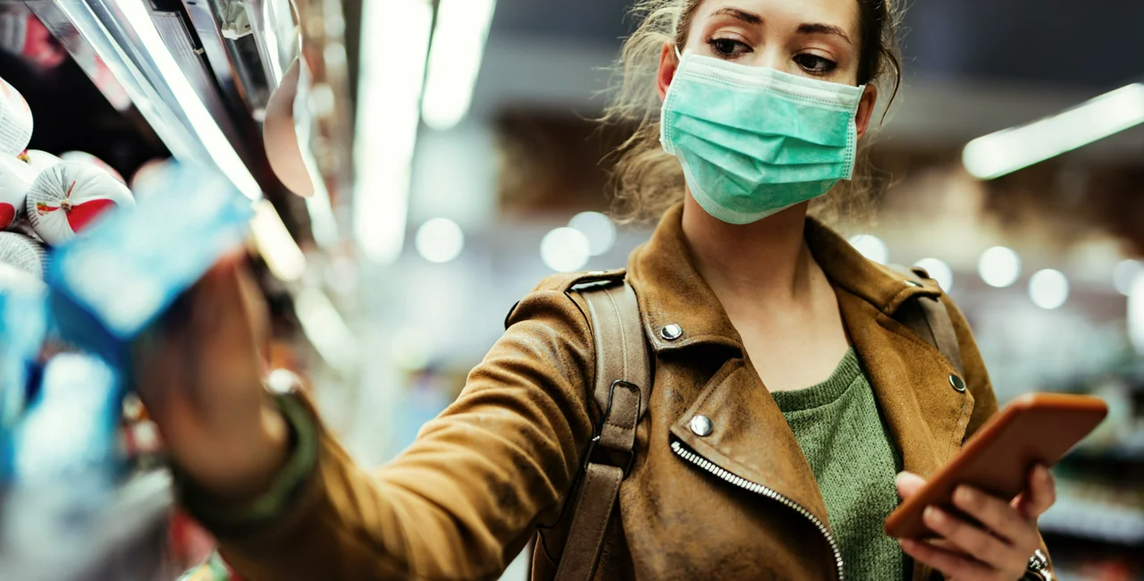 Young woman wearing a face mask in a supermarket via iStock / Drazen Zigic