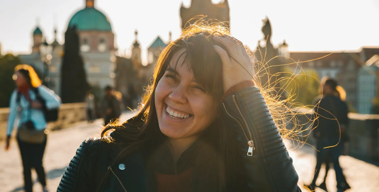 iStock-1174934338 Vera_Petrunina Woman portrait at sunrise with messy hair due to wind stock photo woman happy charles bridge nice