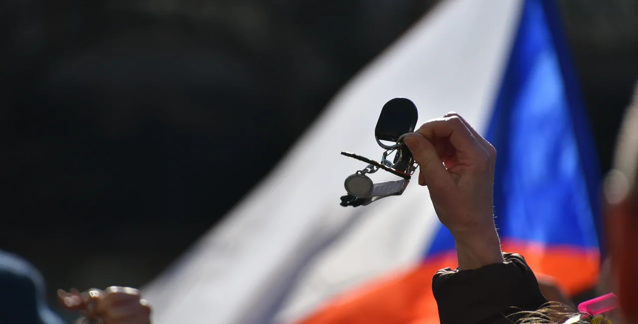 Protestor jangling keys in front of a Czech flag. Photo: Shutterstock / Helena Zezulkova